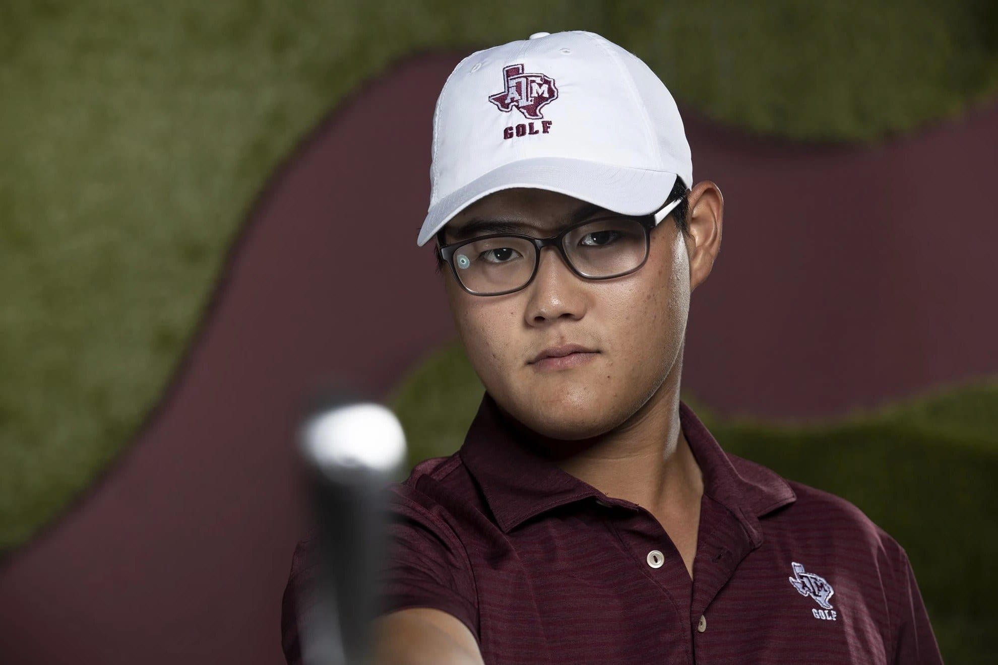 Golf coach Jimmy Lee pointing a club toward the camera